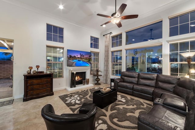 tiled living room with ceiling fan, a towering ceiling, and crown molding