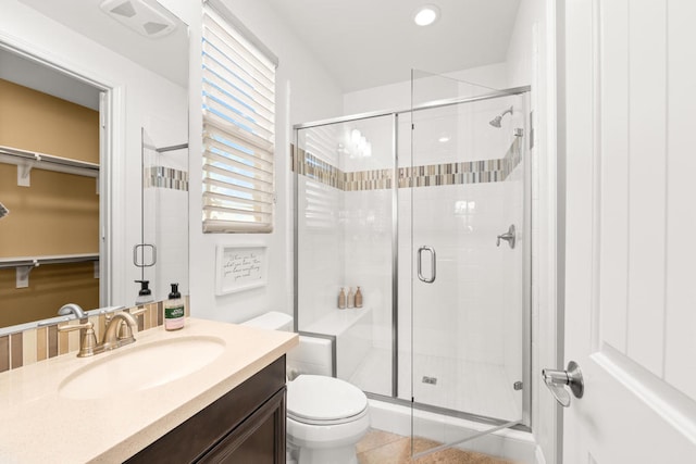 bathroom with tile patterned flooring, a shower with shower door, vanity, and toilet