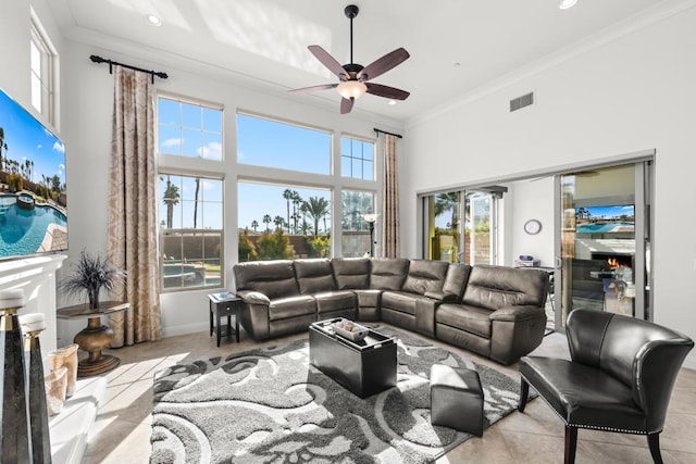 living room featuring crown molding, light tile patterned flooring, a towering ceiling, and ceiling fan