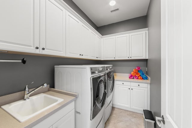 laundry area with cabinets, light tile patterned flooring, separate washer and dryer, and sink