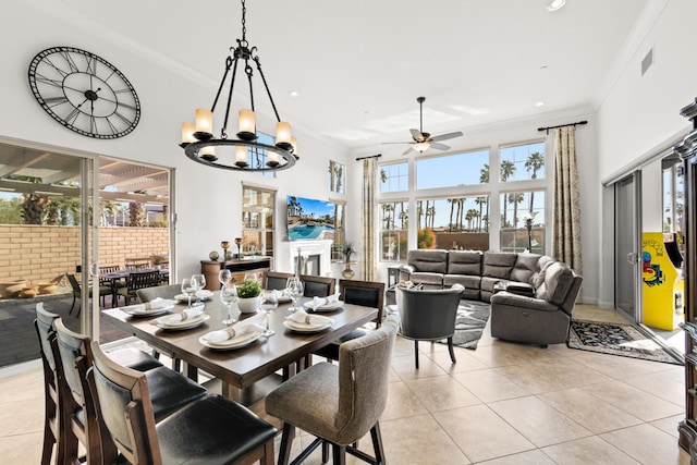 tiled dining space with ceiling fan with notable chandelier and ornamental molding