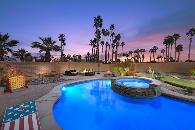 pool at dusk with an in ground hot tub, a patio area, and a fire pit