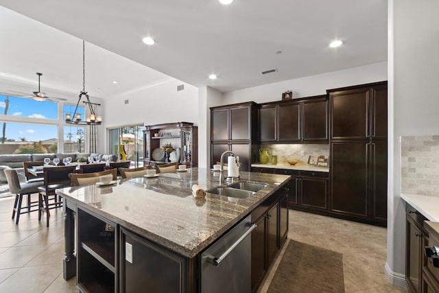 kitchen with hanging light fixtures, decorative backsplash, stainless steel dishwasher, a kitchen island with sink, and sink