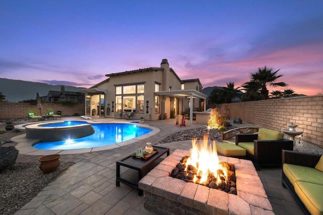 pool at dusk featuring a patio, an in ground hot tub, and an outdoor fire pit