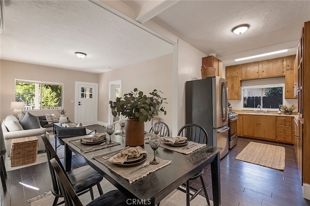 dining space with a textured ceiling, dark hardwood / wood-style floors, beam ceiling, and sink