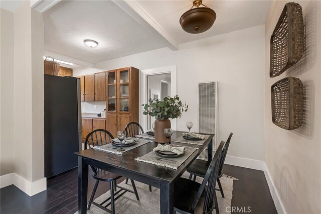 dining area with beamed ceiling and dark hardwood / wood-style floors