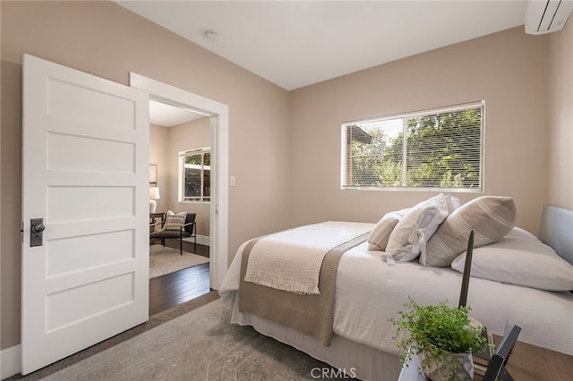 bedroom with hardwood / wood-style flooring and an AC wall unit