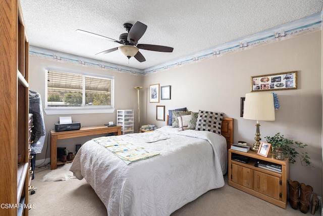 carpeted bedroom featuring ceiling fan and a textured ceiling