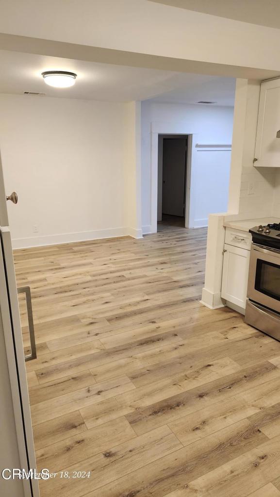 kitchen with white cabinetry, stainless steel range, and light hardwood / wood-style flooring