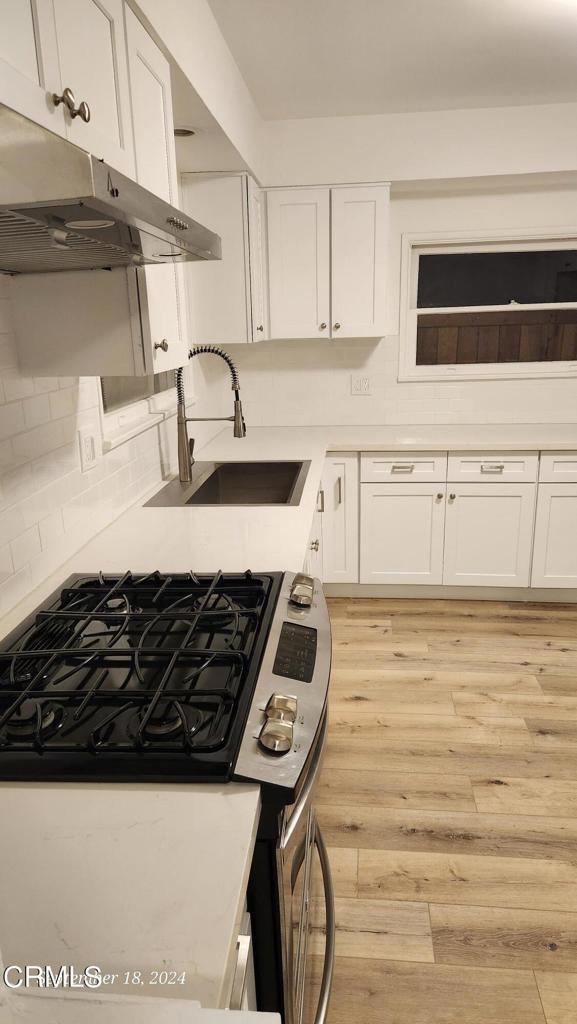 kitchen featuring gas stove, sink, and white cabinets