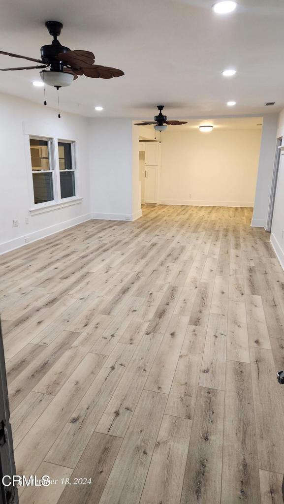 unfurnished living room featuring ceiling fan and light hardwood / wood-style floors