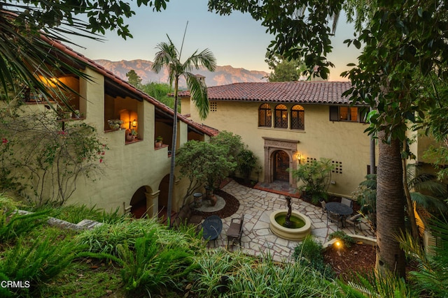 back house at dusk featuring a patio area