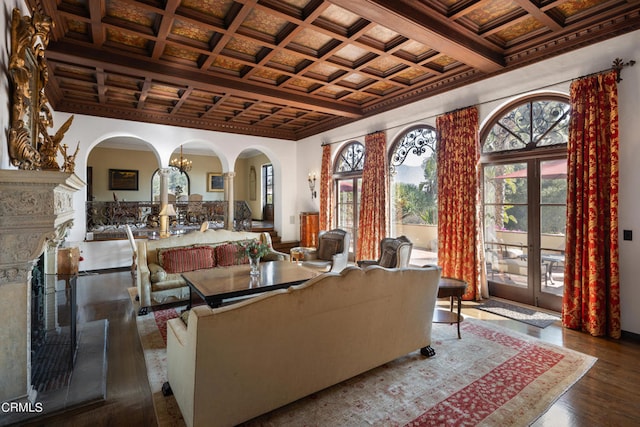 living room featuring beam ceiling, a high end fireplace, coffered ceiling, an inviting chandelier, and dark hardwood / wood-style flooring