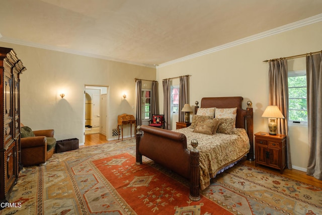 bedroom with connected bathroom, light hardwood / wood-style floors, and ornamental molding