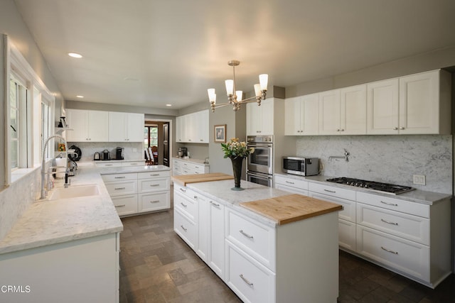 kitchen featuring pendant lighting, appliances with stainless steel finishes, sink, and white cabinetry