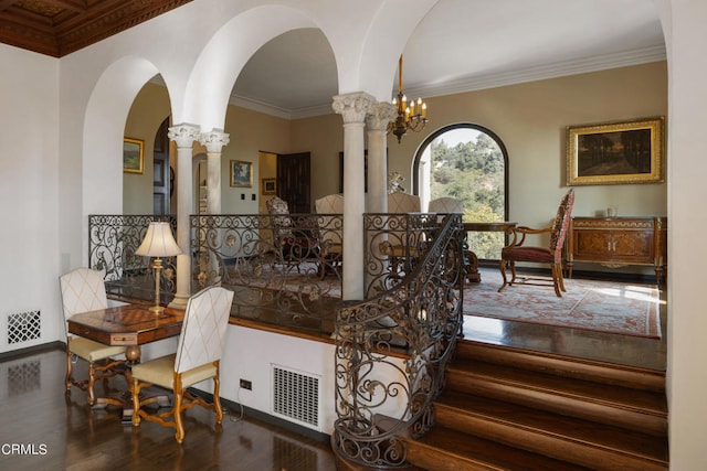 stairway featuring wood-type flooring, decorative columns, ornamental molding, and an inviting chandelier