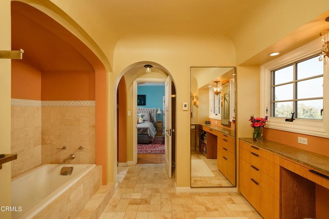 bathroom featuring vanity and a relaxing tiled tub