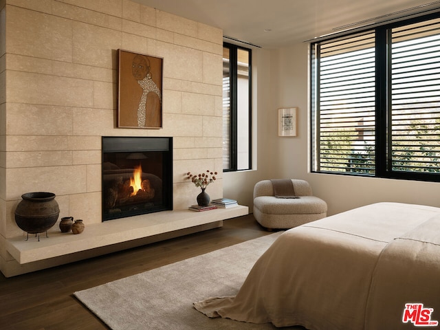 bedroom with multiple windows, a fireplace, and dark wood-type flooring