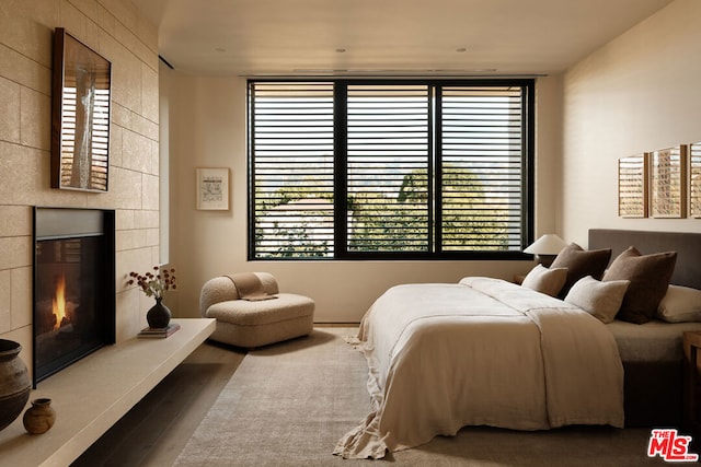 bedroom with hardwood / wood-style floors and a tiled fireplace