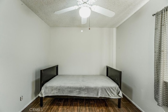 bedroom with ceiling fan, dark hardwood / wood-style floors, and a textured ceiling