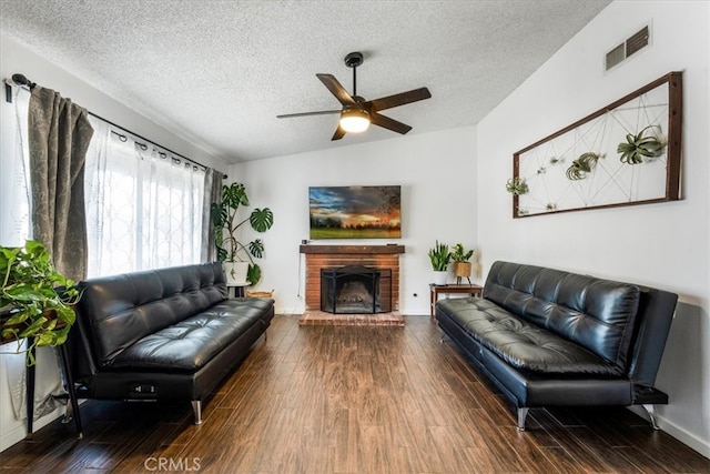 living room with wood-type flooring, a textured ceiling, lofted ceiling, and a brick fireplace