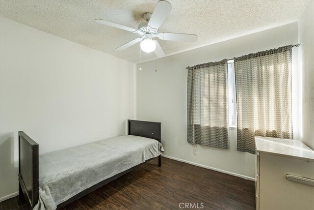 bedroom with ceiling fan, dark hardwood / wood-style floors, and a textured ceiling