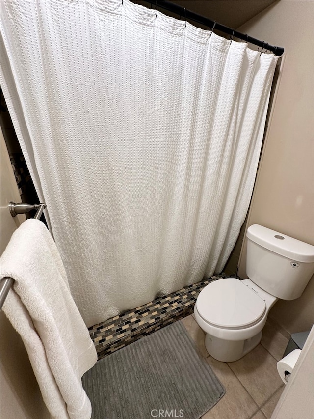 bathroom featuring walk in shower, tile patterned flooring, and toilet