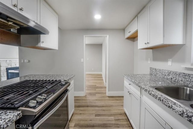 kitchen featuring range with gas cooktop, sink, light stone counters, and white cabinetry