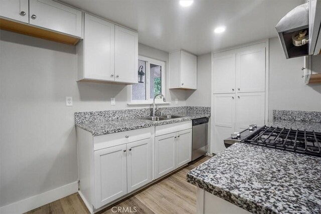 kitchen featuring ventilation hood, white cabinetry, stainless steel dishwasher, and sink