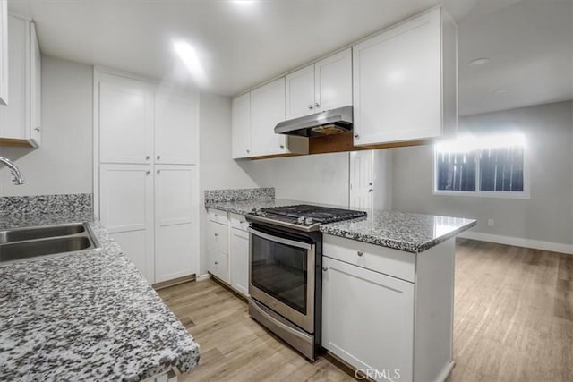 kitchen with white cabinets, light wood-type flooring, sink, and gas range