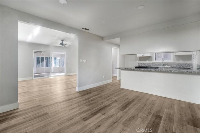 unfurnished living room featuring ceiling fan, sink, and light hardwood / wood-style flooring