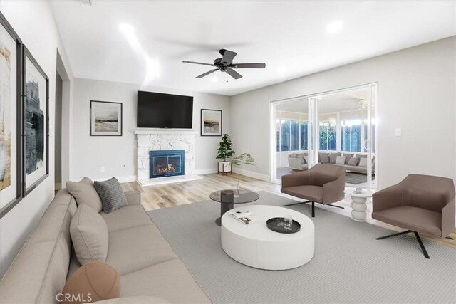 living room featuring ceiling fan, a fireplace, and hardwood / wood-style floors