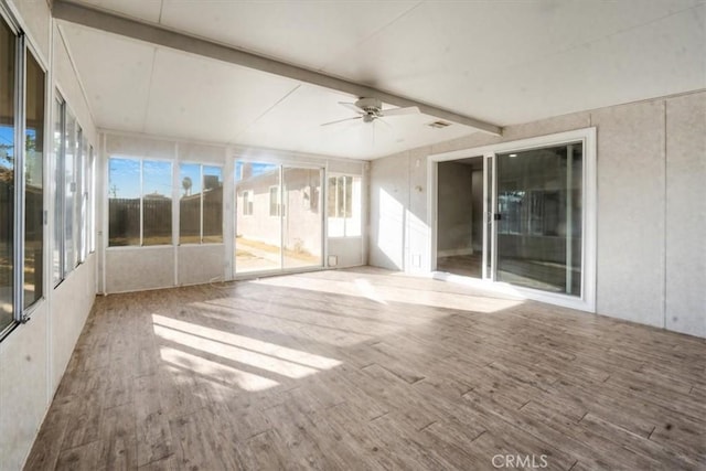 unfurnished sunroom featuring ceiling fan, beam ceiling, and a healthy amount of sunlight