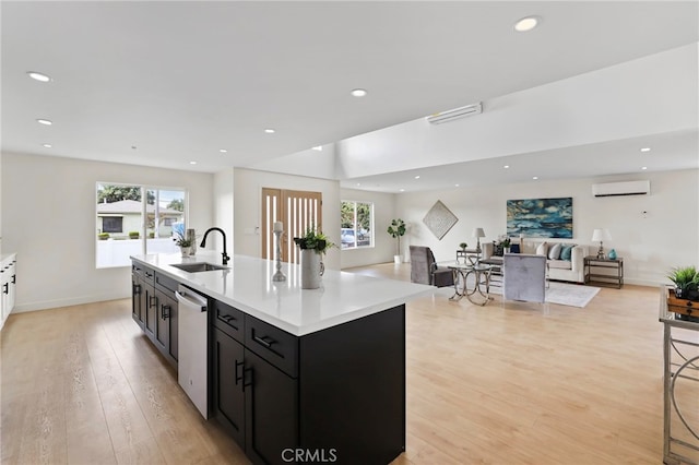 kitchen featuring a wall mounted AC, a kitchen island with sink, sink, and a wealth of natural light