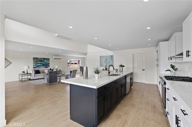 kitchen featuring light wood-type flooring, a kitchen island with sink, sink, and white cabinets