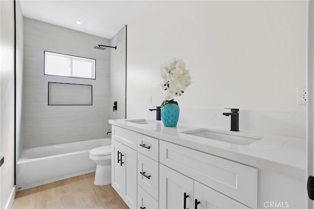 full bathroom featuring tiled shower / bath, vanity, hardwood / wood-style floors, and toilet