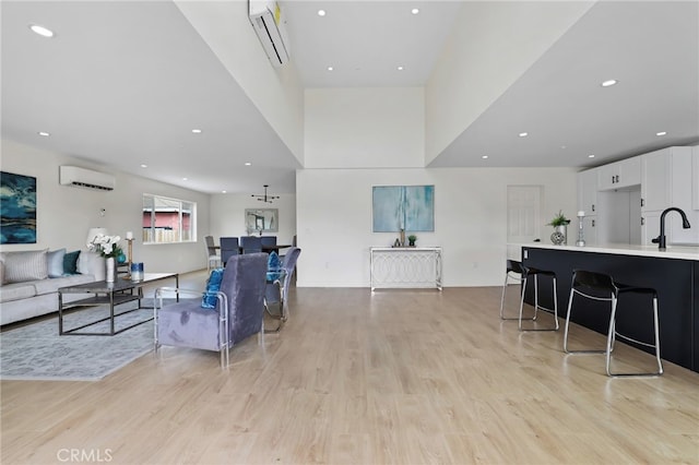 living room featuring light hardwood / wood-style flooring, sink, and a wall mounted AC