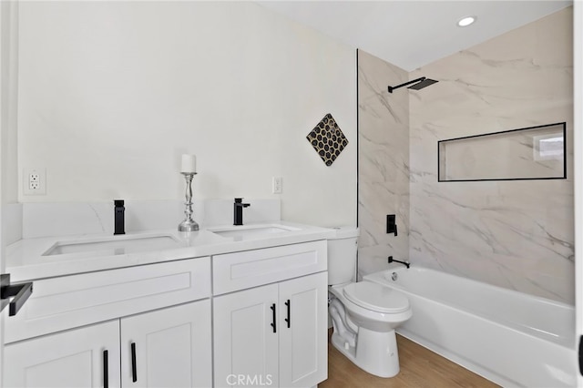 full bathroom featuring wood-type flooring, tiled shower / bath, vanity, and toilet