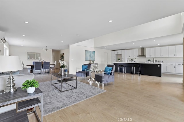 living room with an AC wall unit and light hardwood / wood-style floors