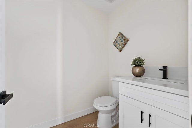 bathroom with hardwood / wood-style flooring, vanity, and toilet