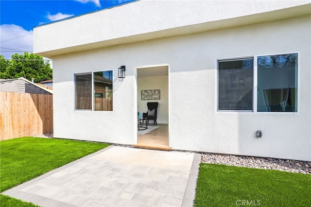 property entrance with a lawn and a patio area