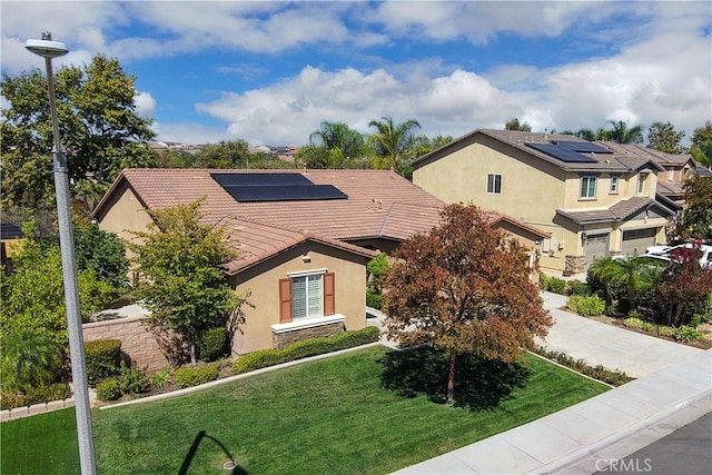 view of front facade with a front lawn, solar panels, and a garage