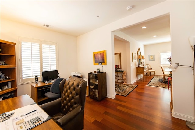 home office with dark wood-type flooring and a healthy amount of sunlight