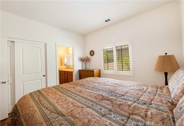 bedroom with a closet, ensuite bathroom, and sink