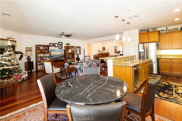 dining area featuring dark wood-type flooring, ceiling fan, and sink