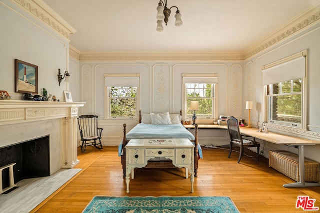 bedroom featuring light hardwood / wood-style floors, a fireplace, and crown molding