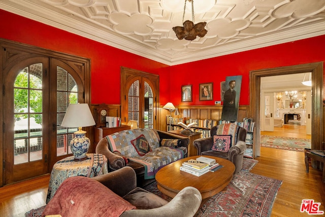 living room with a chandelier, light hardwood / wood-style floors, french doors, and crown molding