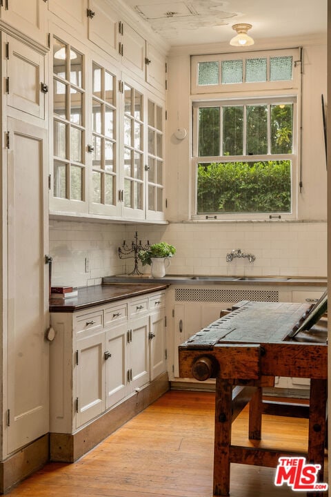 kitchen featuring white cabinets, light hardwood / wood-style floors, and tasteful backsplash