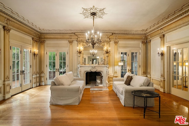 living room with french doors, an inviting chandelier, ornamental molding, and wood-type flooring