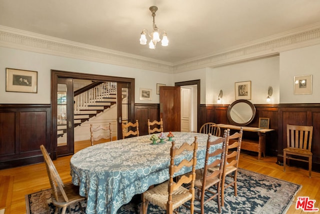 dining space featuring ornamental molding, light hardwood / wood-style flooring, and a notable chandelier